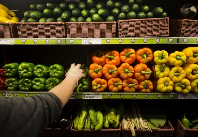 An employee stocks the shelves with fresh peppers in the produce section at Whole Foods in Dublin, Ohio on Friday, November 7, 2014.