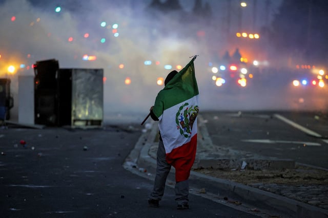 A protester holds a Mexican flag during a standoff between police and protesters in Compton, California, on Saturday.