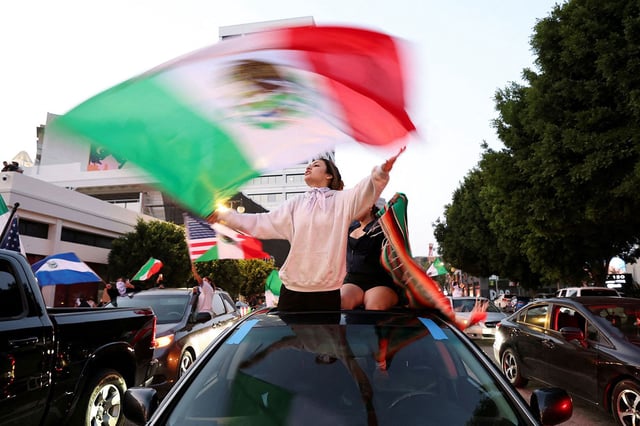A demonstrator waves a Mexican flag during a protest against federal immigration sweeps, in downtown Los Angeles on Monday.