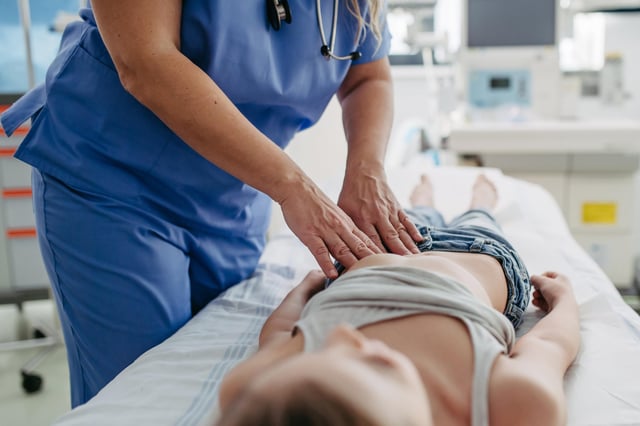 A stock image shows a doctor pressing on a young woman&#39;s appendix.