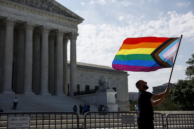 Same-sex marriage supporter Vin Testa, of Washington, DC, waves a LGBTQIA pride flag in front of the U.S. Supreme Court Building as he makes pictures with his friend Donte Gonzalez to celebrate the anniversary of the United States v. Windsor and the Obergefell v. Hodges decisions on June 26, 2023 in Washington, DC.