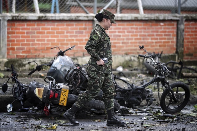 A soldier walks past motorcycle wreckage after a bomb exploded in Cali, Colombia, Tuesday, June 10, 2025. (AP Photo/Santiago Saldarriaga)