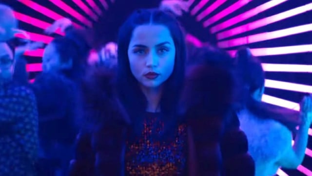 dark haired young woman against purple-hued night club background