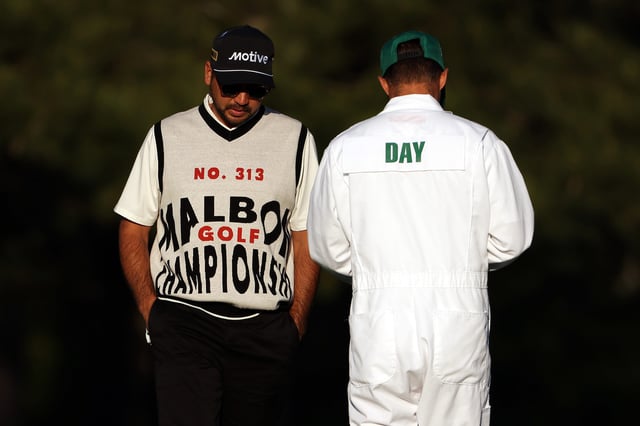 Jason Day (wearing a Malbon sweater) and his caddie, Luke Reardon, wait on the 15th hole during the continuation of the first round of the 2024 Masters Tournament at Augusta National Golf Club.