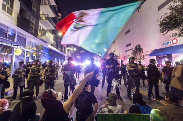 Demonstrators waving a Mexico flag confront police officers during a demonstration against immigration raids in Los Angeles on June 9, 2025
