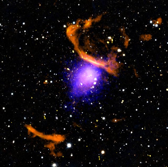 A radio glow surrounds PLCK G287.0+32.9, seen here in a composite image with data from NASA’s Chandra X-ray telescope (purple) and the MeerKAT radio array (orange). Credit: X-ray: NASA/CXC/SAO/K. Rajpurohit et al.; Optical: PanSTARRS; Radio: SARAO/MeerKAT; Image processing: NASA/CXC/SAO/N. Wolk