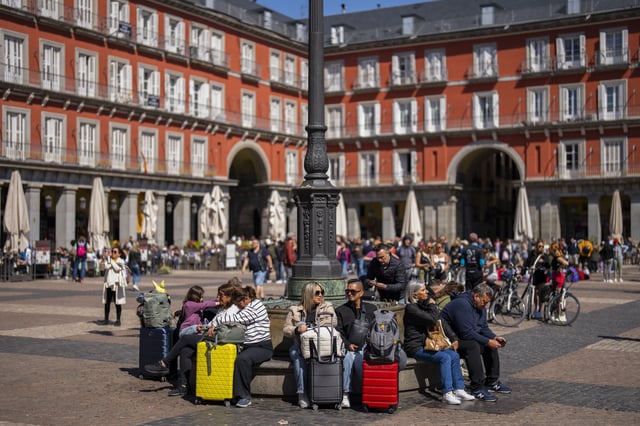 FILE - Tourists sit on a public bench at Plaza Mayor in downtown Madrid, Spain, April 29, 2024. (AP Photo/Bernat Armangue, File)