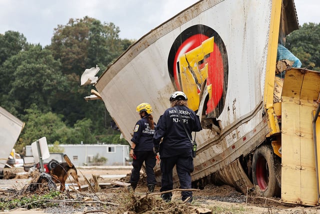 Members of the FEMA Urban Search and Rescue Task Force search a flood damaged area with a search canine in the aftermath of Hurricane Helene along the Swannanoa River on October 4, 2024, in Asheville, North Carolina.