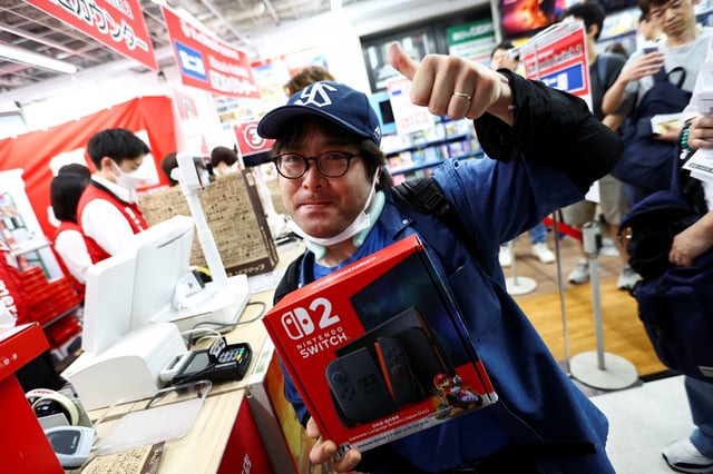 Shopper Takafumi Yamaguchi, 42, gestures while holding Nintendo Switch 2 game console as Nintendo starts selling the new consoles globally, at an electronics store in Tokyo, Japan June 5, 2025.  REUTERS/Issei Kato/File Photo