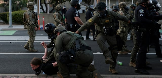 Des membres de la police des frontières plaquent au sol une manifestante à Santa Ana, en Californie, près du bureau des Services de l'Immigration, le 9 juin 2025, lors de protestations contre la politique migratoire de Donald Trump