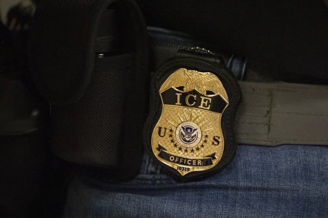 A federal agent wears a badge of Immigration and Customs Enforcement while standing outside an immigration courtroom at the Jacob K. Javits Federal Building in New York, Tuesday, June 10, 2025.
