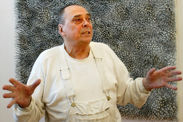 FILE - In this Wednesday, March 9, 2005 file picture German artist Guenther Uecker, one of the country's most important post-war artists who was famous for his large-format nail reliefs, stands in front of his artwork 'Feld' (field) in Berlin, Berlin. (AP Photo/Jockel Finck, File)