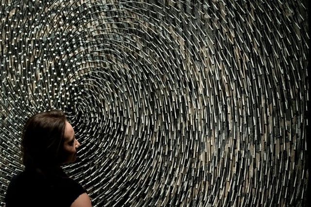 An employee poses with an artwork by German sculptor Gunther Uecker entitled 'Doppelspirale' ahead of an art sale at Christie's in London on March 3, 2017