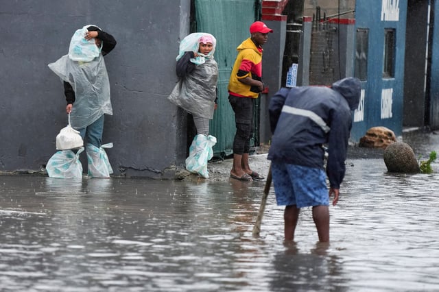 Residents walk across a flooded road following severe weather with heavy rain from a cold front in Masiphumelele, Cape Town, South Africa on May 20, 2025. REUTERS/Nic Bothma