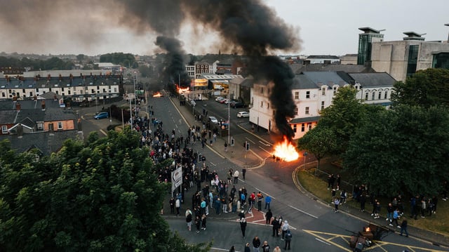 Drohnenansicht von aufsteigendem Rauch und Feuer inmitten von Unruhen in Ballymena (Nordirland).