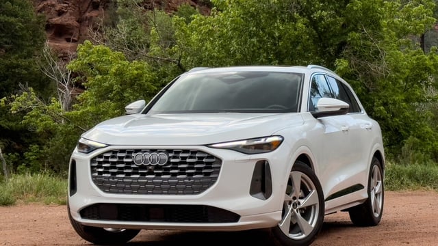 A white Audi Q5 parked on some dirt next to some trees