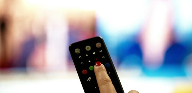 Une personne tient une télécommande pointée vers un écran de télévision, à Paris le 15 janvier 2025