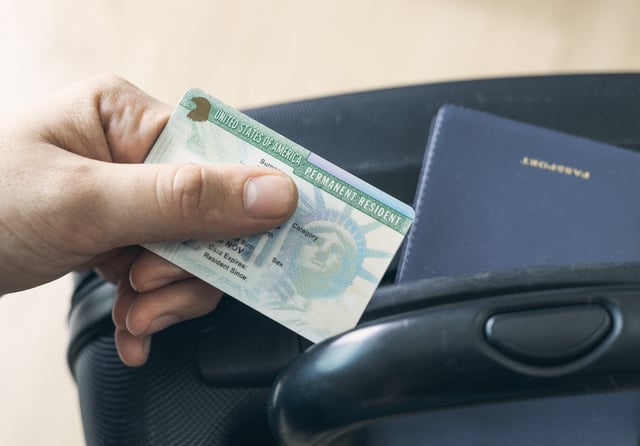 A man holds a United States Permanent Resident card, otherwise known as a Green Card. Image for illustration purposes only.