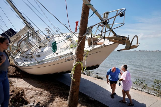 Keith and his wife Angel, check on their sailboat that ended up on the sidewalk near Sarasota Bay after Hurricane Milton made landfall in Sarasota on Oct. 10, 2024. (Carline Jean/South Florida Sun Sentinel)