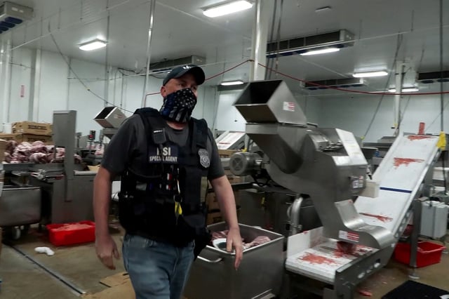 An agent passes meat being prepared during a raid by U.S. Immigration and Customs Enforcement (ICE) at a Glenn Valley Foods meat production plant in Omaha, Nebraska, U.S. June 10, 2025 in a still image from video.  U.S. Immigration and Customs Enforcement/Handout via REUTERS