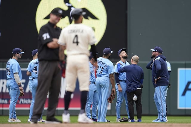 Toronto Blue Jays right fielder Nathan Lukes (38), middle right, is looked at by a trainer after a collision with teammate second baseman Ernie Clement (22) during the sixth inning of a baseball game against the Minnesota Twins, Sunday, June 8, 2025, in Minneapolis. (AP Photo/Abbie Parr)
