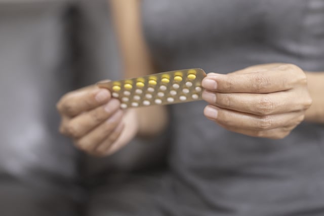 Woman holding combined oral contraceptive pill.