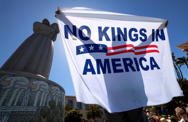Dan Cummings holds up a flag during the ‘Not on Our Watch’ anti-Trump protest and march at Waterfront Park in downtown San Diego on Saturday, April 19, 2025. (Hayne Palmour IV / For The San Diego Union-Tribune)