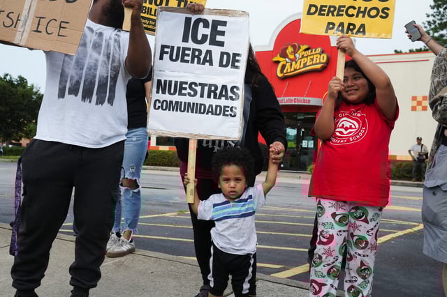 A child is assisted while holding a placard that reads "ICE, out of our communities" during a protest against federal immigration sweeps, in Atlanta, Georgia, U.S. June 10, 2025. REUTERS/Megan Varner