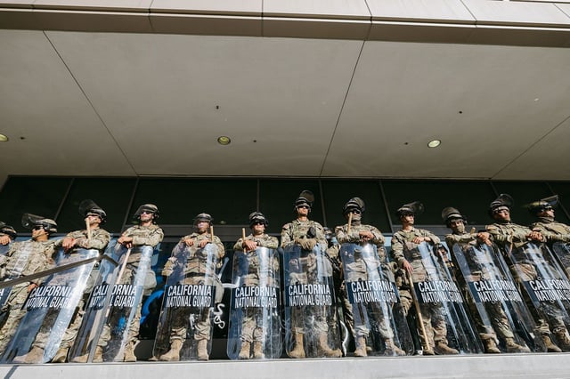 Members of the California National Guard stand guard outside the Federal Building before a curfew takes effect in Los Angeles on June 10, 2025, following days of protests in response to federal immigration operations that saw clashes spread across downtown. The overnight curfew followed days of unrest sparked by federal immigration operations, with Mayor Karen Bass stating the measure aimed to "stop the vandalism, to stop the looting" after prolonged protests. (Photo by David Pashaee / Middle East Images via AFP) (Photo by DAVID PASHAEE/Middle East Images/AFP via Getty Images)          