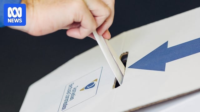 hand puts a ballot into a voting ballot box
