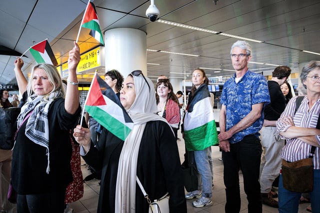 People wave Palestinian flags as participants in the 'Global March to Gaza' depart from Schiphol Airport for Egypt at Schiphol, The Netherlands on Wednesday.