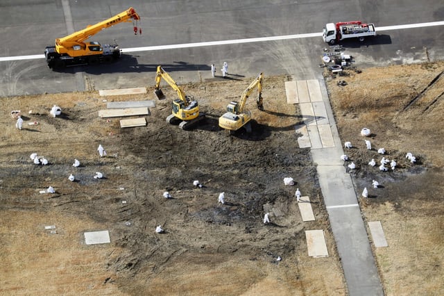 An aerial view shows officials working at the site after removed big wreckage of burnt Japan Airlines' (JAL) Airbus A350 plane after a collision with a Japan Coast Guard aircraft next to it's runway at Haneda international airport in Tokyo, Japan January 7, 2024, in this photo taken by Kyodo. Mandatory credit Kyodo via REUTERS