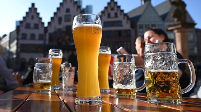 Junge Menschen sitzen an einem Tisch mit gefüllten Biergläsern.