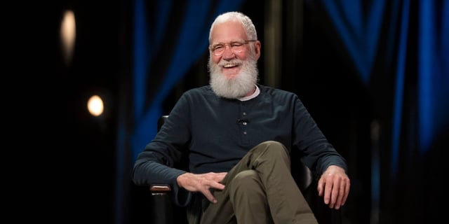 David Letterman sitting in a chair laughing