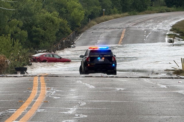A police vehicle blocks a flooded roadway in San Antonio, Texas., where a vehicle was stranded after heavy rains in the city on Thursday, June 12, 2025.