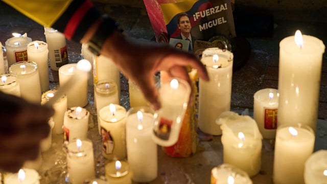 People light candles outside the clinic where Colombian Senator Miguel Uribe Turbay is being treated after being shot