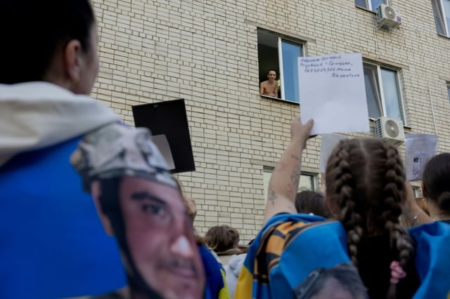 Desperate relatives show  photographs of missing soldiers to a Ukrainian prisoner freed in an exchange with Russia