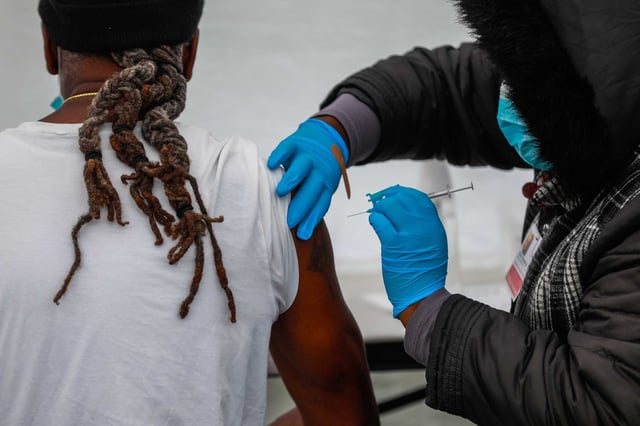 A man receives a COVID-19 vaccine from medical assistant Tiffany Washington, right, outside non-profit Serenity House on Jan. 7, 2022 in Oakland.