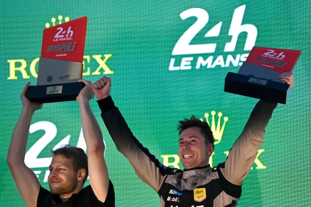 Le pilote britannique de la Cadillac N12 Alex Lynn, qui a décroché la pole position  aux 24 heures du Mans,
aux côté de son manageur d'équipe Sam Hignett sur le podium du circuit le 12 juin 2025