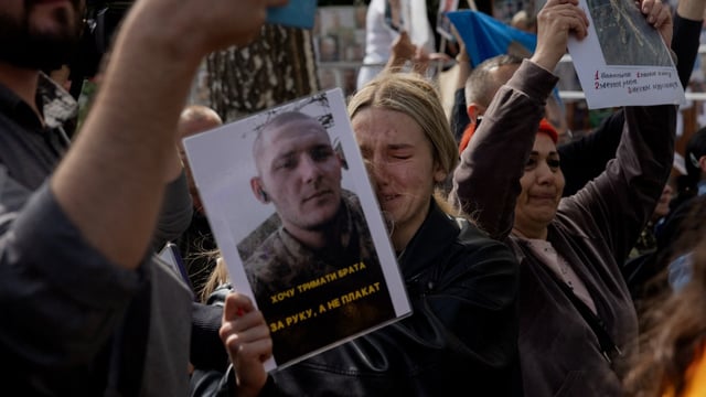 Photos were held aloft as Ukrainian prisoners of war arrived at a hospital