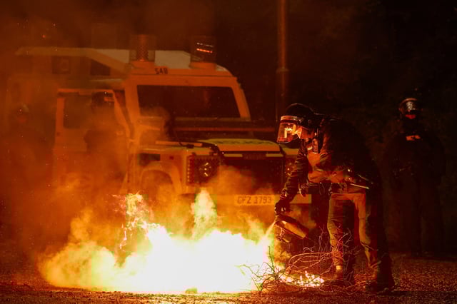 A riot police officer tries to extinguish a fire during the fourth night of unrest following a protest over an alleged sexual assault on a local teenage girl, in Portadown, Northern Ireland, June 12, 2025. REUTERS/Clodagh Kilcoyne