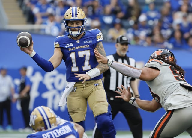 Winnipeg Blue Bombers quarterback Chris Streveler (17) throws to Matthew Peterson (22) as he gets pressure from BC Lions' Jonah Tavai (99) during first half CFL action in Winnipeg Thursday, June 12, 2025. THE CANADIAN PRESS/John Woods
