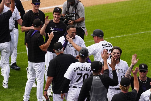 Jun 12, 2025; Denver, Colorado, USA; Colorado Rockies first baseman Orlando Arcia (11) (center) celebrates his two run walk off single with teammates against the San Francisco Giants at Coors Field. Mandatory Credit: Ron Chenoy-Imagn Images