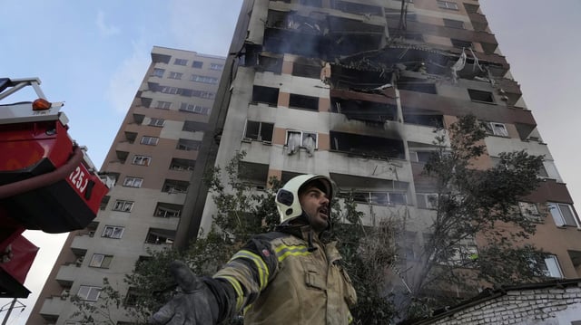 Ein Feuerwehrmann steht vor einem zum Teil zerstörten Hochhaus in Teheran.