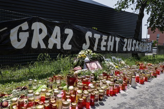Flowers and candles are seen in front of the fences as a banner reads ''Graz standing together'', following a deadly shooting at a secondary school, in Graz, Austria, June 12, 2025. REUTERS/Leonhard Foeger/ File Photo