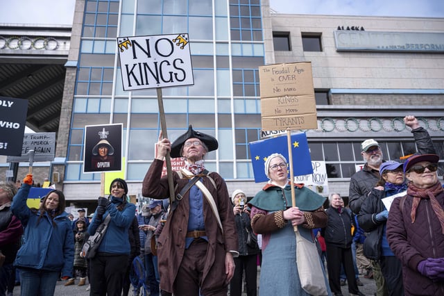 David Teague, a colonial reenactor, holds a sign that says &#34;No Kings&#34; during a protest against President Trump and his policies on Saturday, April 19, 2025 in Anchorage, Alaska.