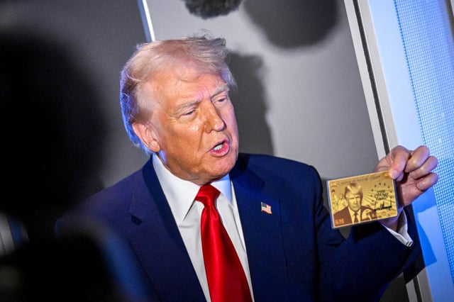 Donald Trump holds the $5 million dollar Gold Card as he speaks to reporters while in flight on board Air Force One, en route to Miami on April 3, 2025.    