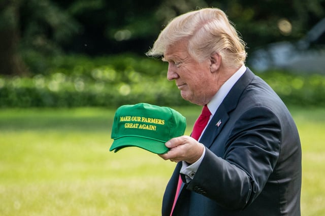 Donald Trump displays caps reading "Make our Farmers Great Again" while walking to board Marine One as he departs the White House on Aug. 30, 2018.