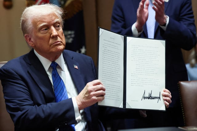 President Donald Trump holds an executive order, at the White House, in Washington, D.C., on March 25, 2025.