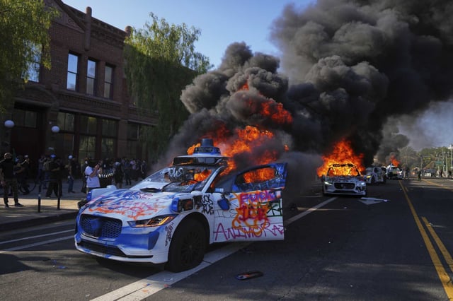 Multiple Waymo taxis burn near the Metropolitan Detention Center of downtown Los Angeles on Sunday, during a weekend of immigration raid protests.
